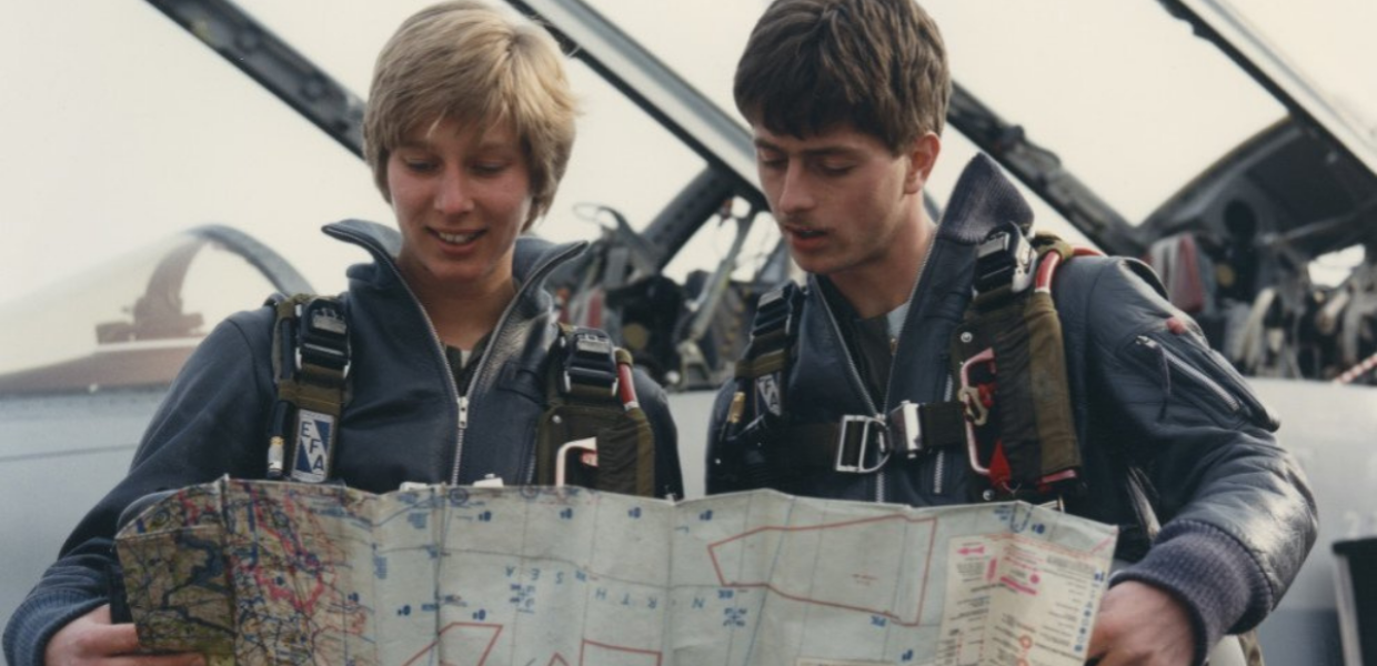 Two pilots, a man and a woman, look at a map
